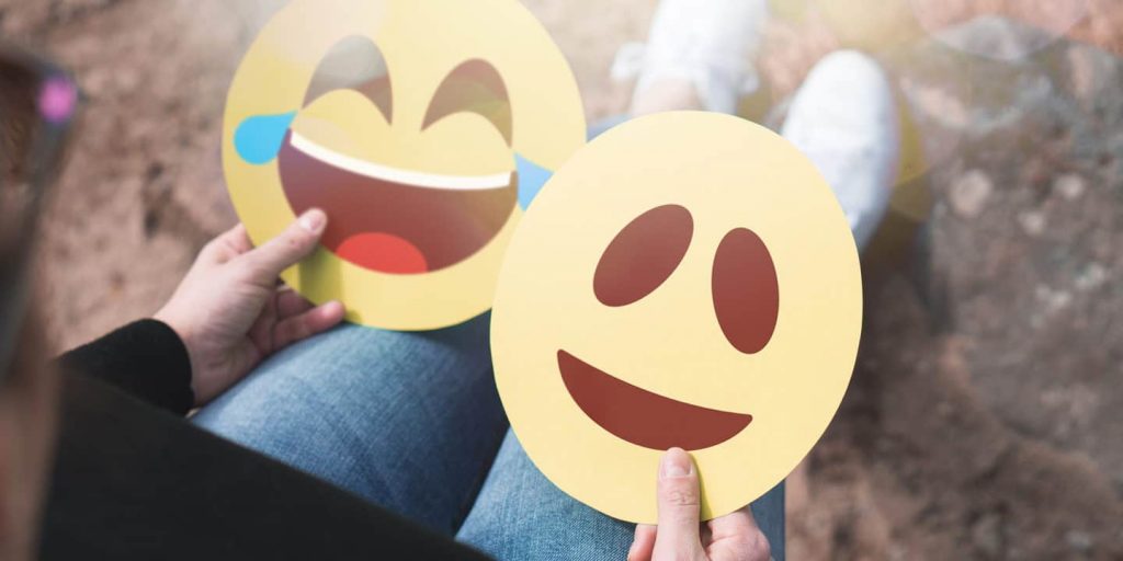 Hand holding two emojis, two smileys