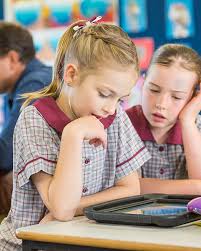 meisje kijkt naar iets op haar tablet, meisje leest op tablet, meisje in de klas