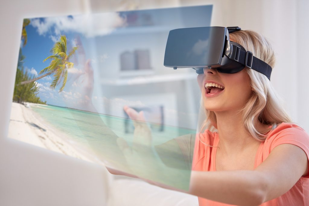 technology, augmented reality, cyberspace, entertainment and people concept - happy young woman wearing virtual headset or 3d glasses with exotic tropical beach projection at home