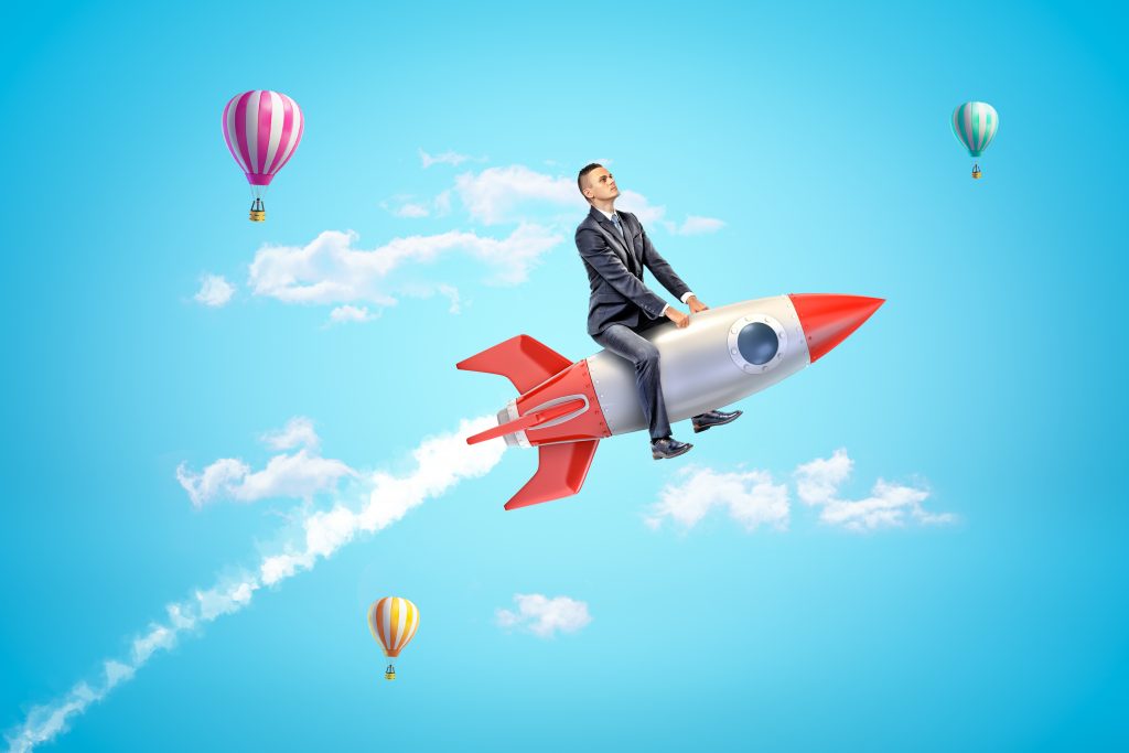 man riding rocket with hot air balloons in the background