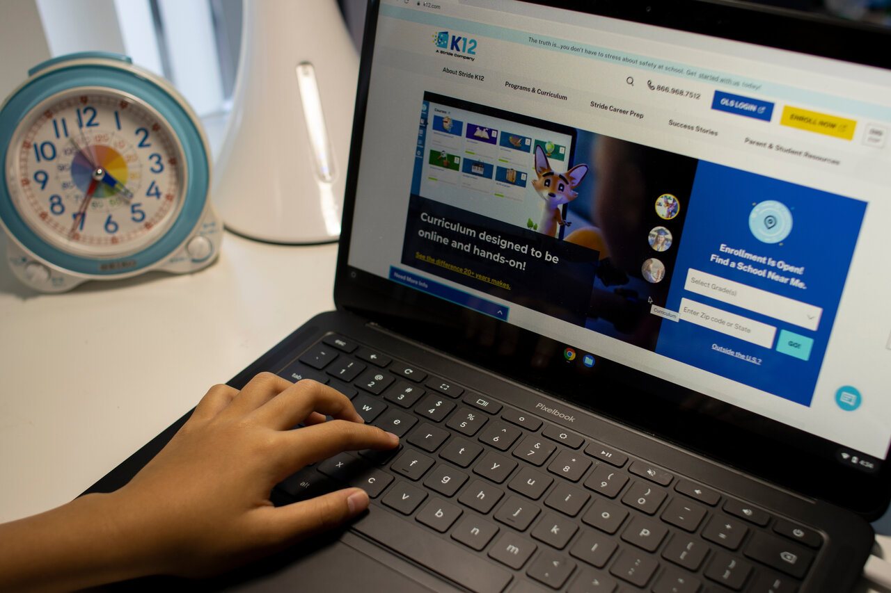 hand typing on a Chromebook with a watch beside it 